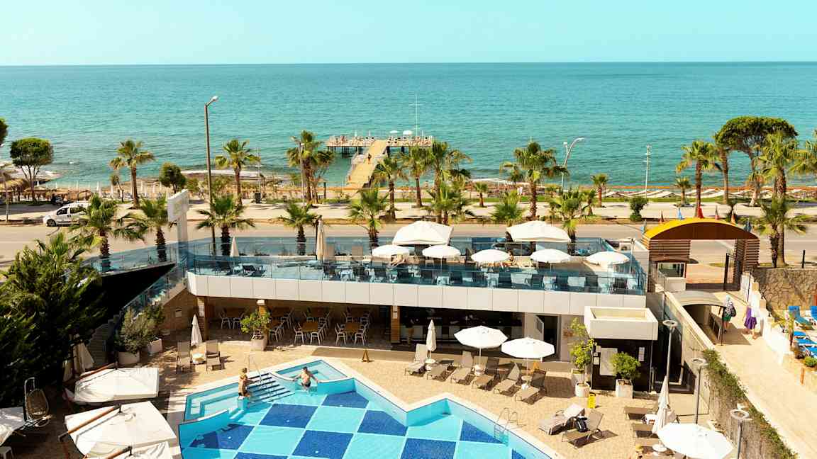 Utsikt fra hotellet mot havet med basseng, terrasse og brygge. (AI-generert tekst)