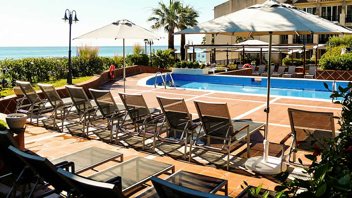 Et utendørsbasseng med solsenger og parasoller. (AI-generert tekst)