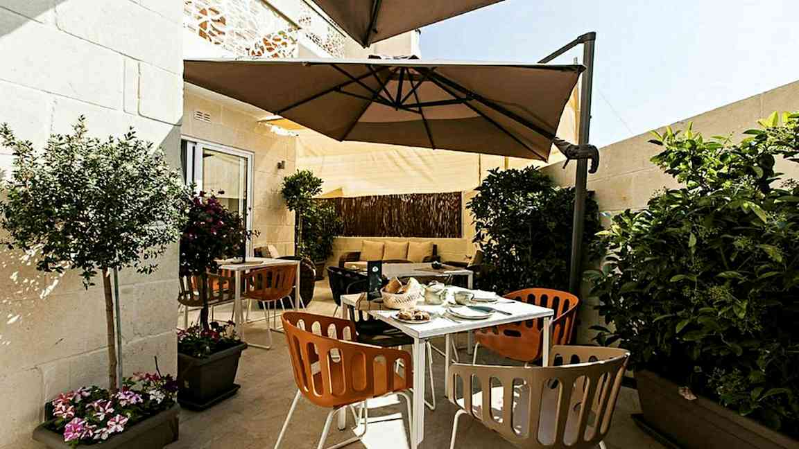 En terrasse med utemøbler, parasoll og planter. (AI-generert tekst)