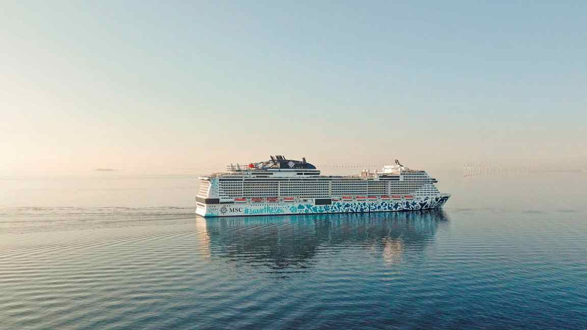 Et cruiseskip på åpent hav med vindmøller i det fjerne. (AI-generert tekst)