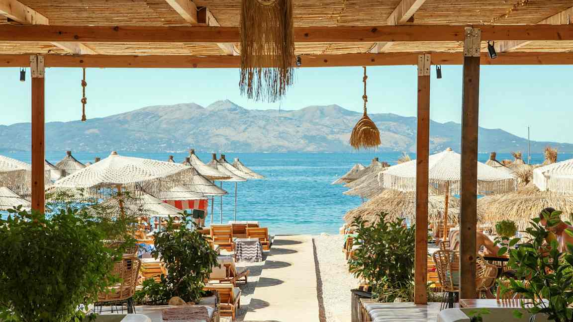 Strandutsikt med parasoller, solsenger og havet i bakgrunnen. (AI-generert tekst)