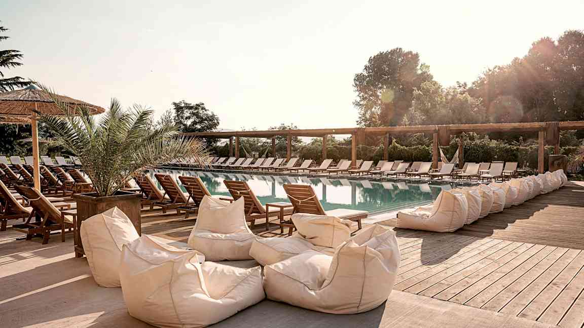 Et utendørs svømmebasseng omgitt av solsenger og sitteputer. (AI-generert tekst)