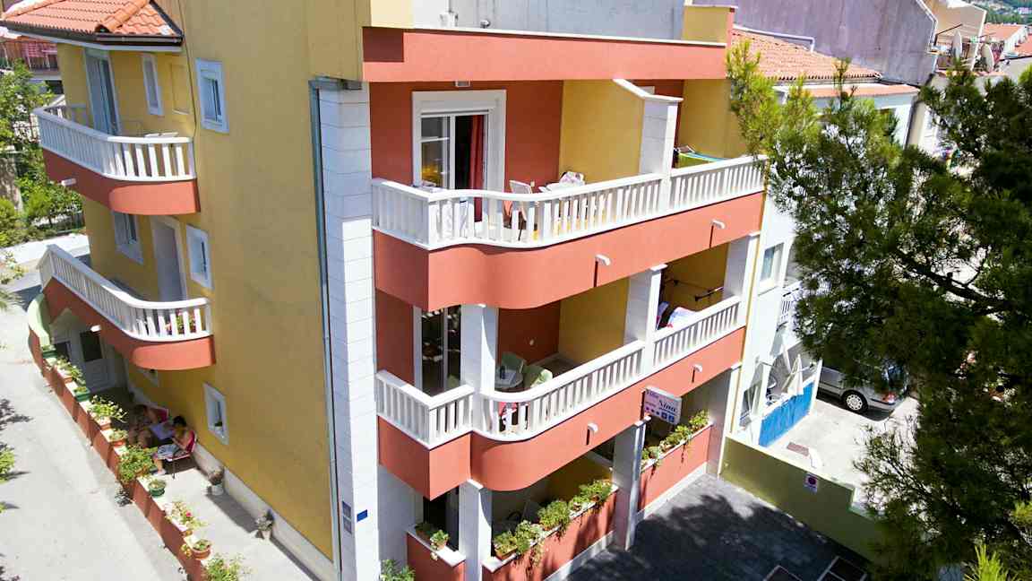 En bygning med gul og rød fasade, balkonger og en liten indre gårdsplass. (AI-generert tekst)