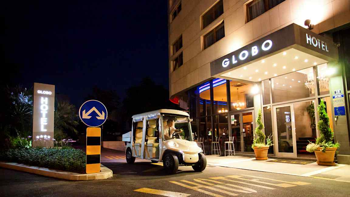 Et hotell sett om natten med navnet Globo, en elbil er parkert foran inngangen. (AI-generert tekst)