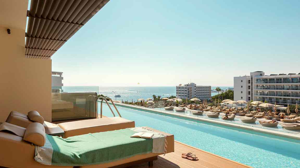 Solstoler og basseng med utsikt over havet på en ferieby. (AI-generert tekst)