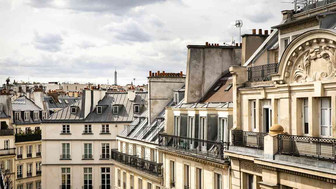 Bilde av parisiske bygninger med typiske tak, med Eiffeltårnet synlig i bakgrunnen. (AI-generert tekst)