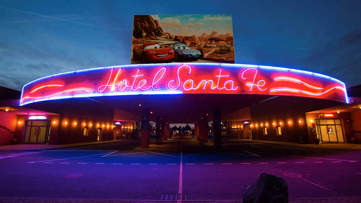 Neonskiltet over inngangen til Hotel Santa Fe med Disney/Pixar-biler på plakaten over. (AI-generert tekst)