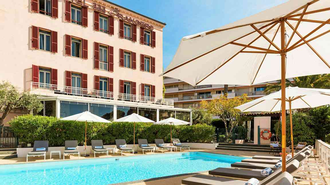 Hotellbygning med basseng og solsenger foran. (AI-generert tekst)