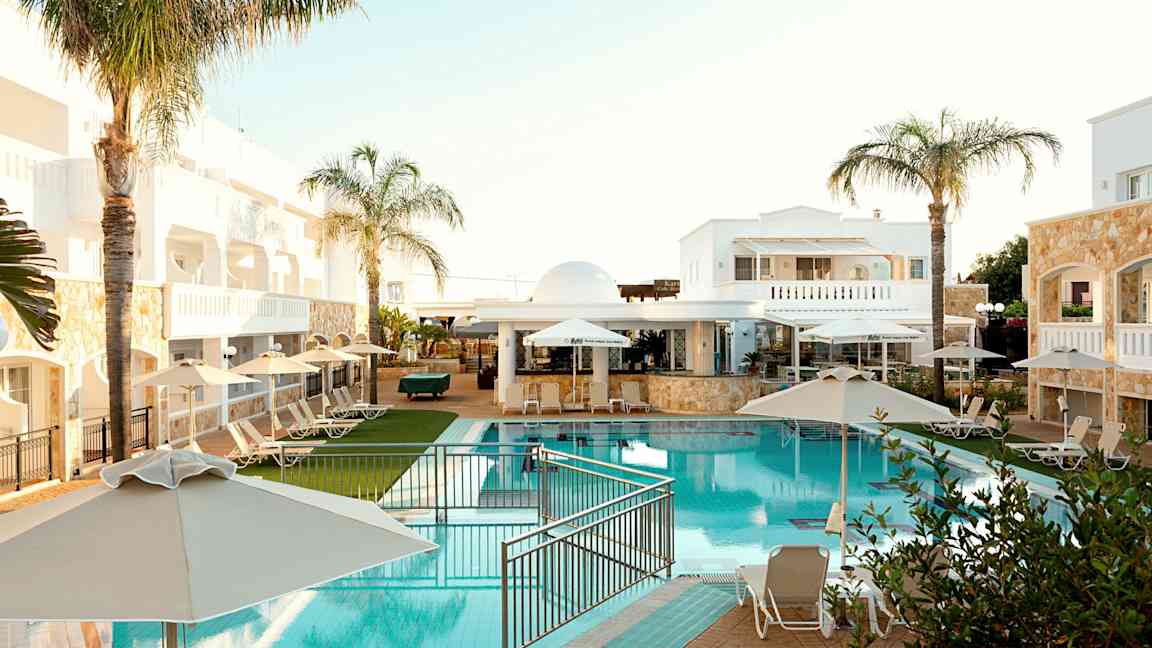 Hotellområde med basseng, solsenger og parasoller. (AI-generert tekst)