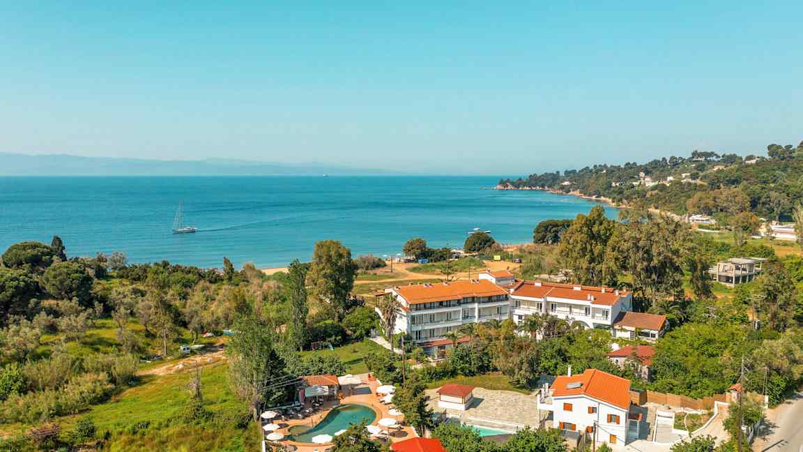 Landskapsbilde som viser bygninger med røde tak nær en kyst med havutsikt. (AI-generert tekst)