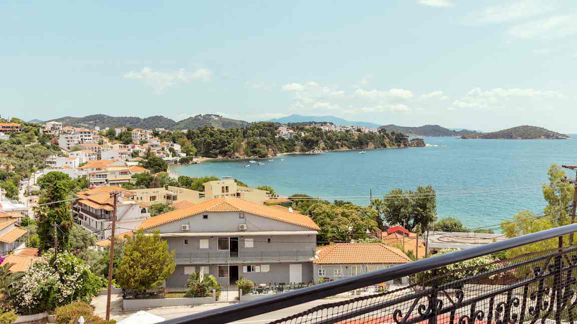 Utsikt over en kystby med røde tak og havet i bakgrunnen. (AI-generert tekst)