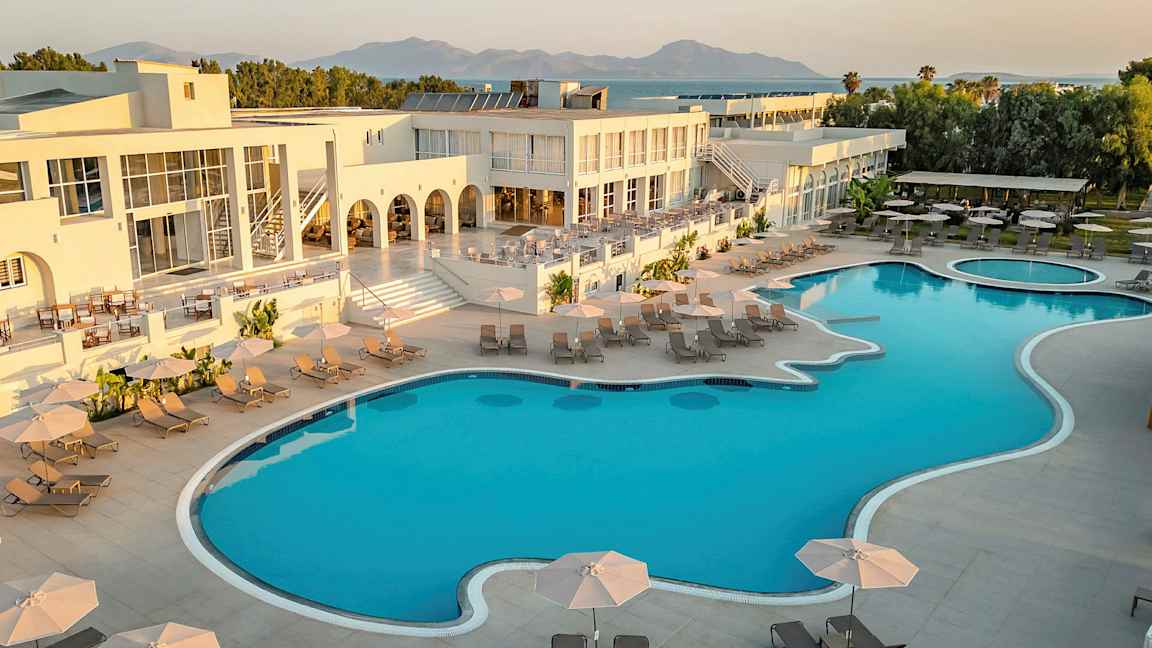 Hotellkompleks med et stort basseng, solsenger og parasoller. (AI-generert tekst)