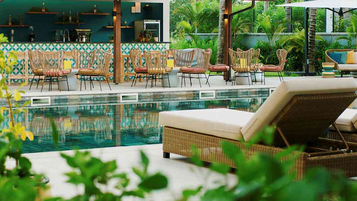 Et utendørs svømmebasseng med solsenger og sittegrupper ved en bar. (AI-generert tekst)