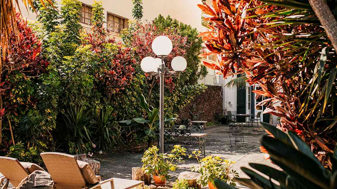 En solfylt gårdsplass med hagemøbler og beplantning. (AI-generert tekst)