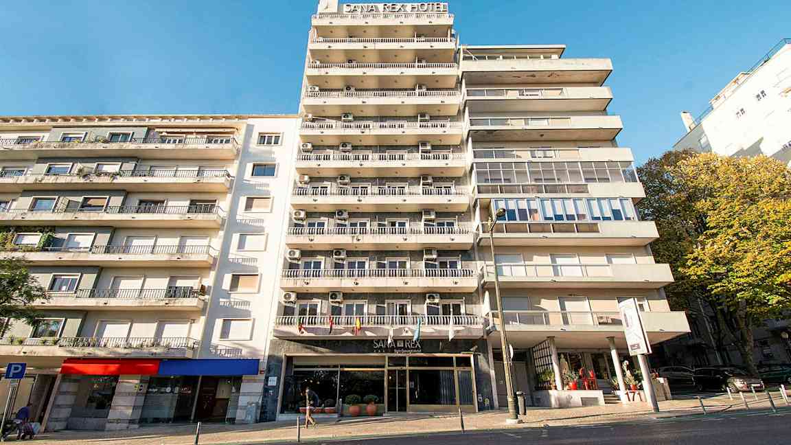 Leilighetsbygg med hotelskilt og balkonger under en klar blå himmel. (AI-generert tekst)