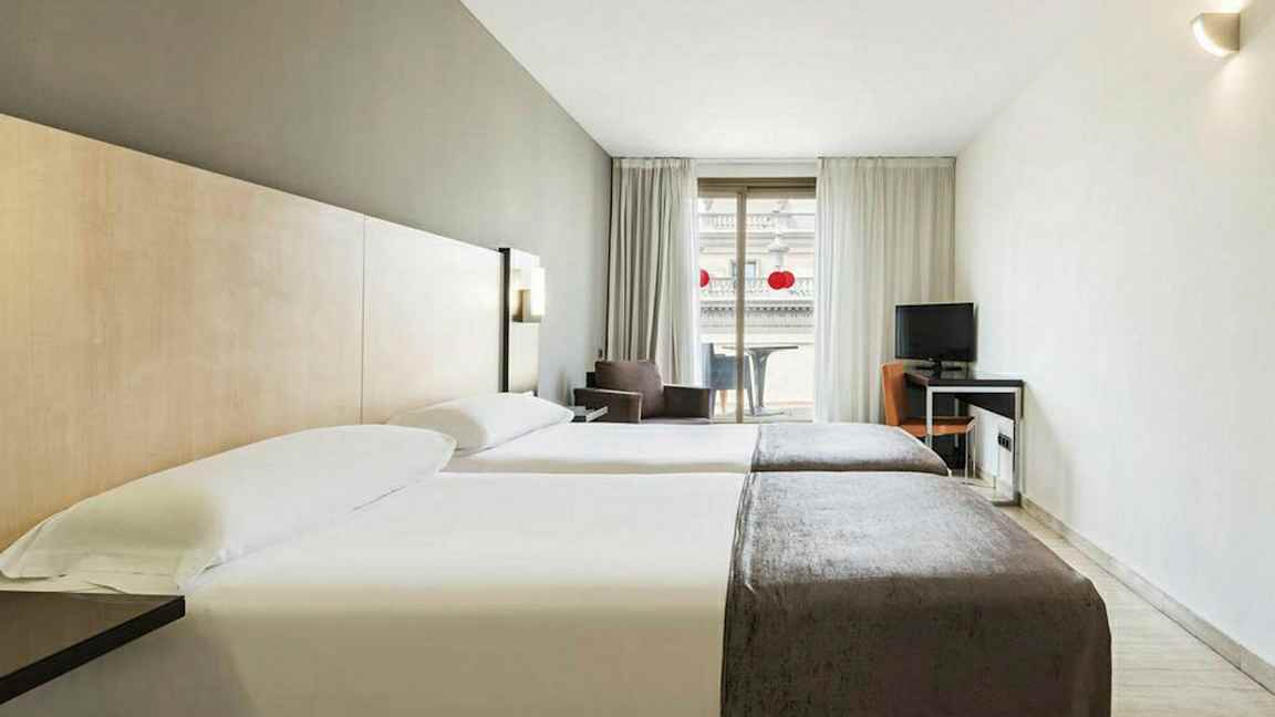 Hotellrom med to enkeltsenger, skrivebord og balkong. (AI-generert tekst)