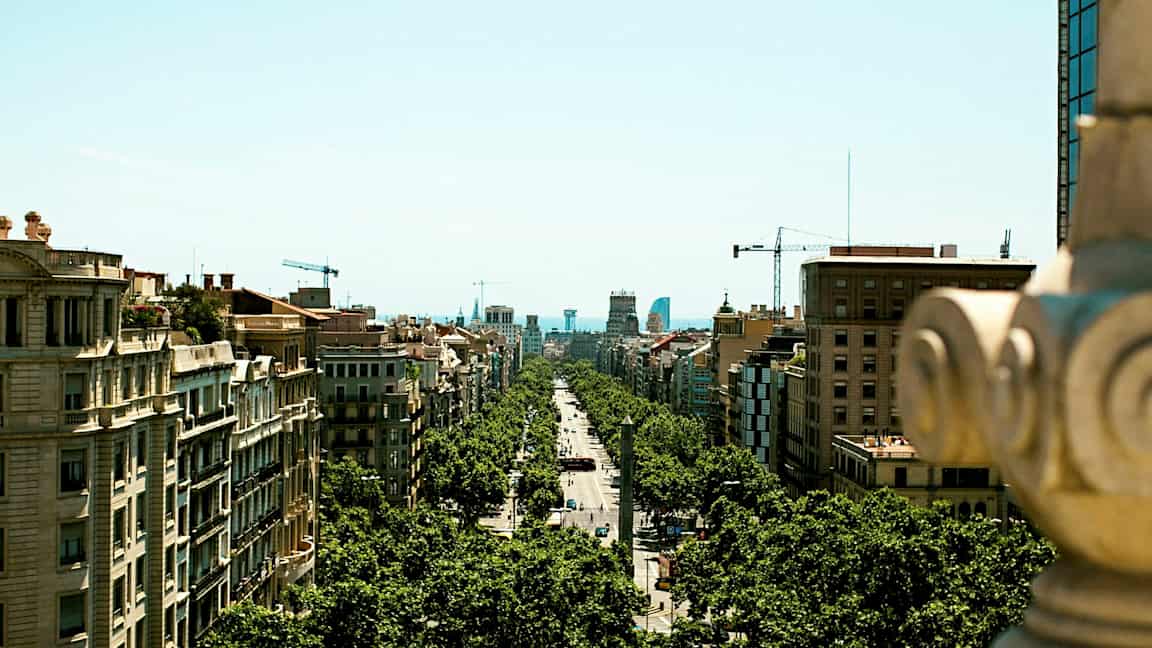 Utsikt over en bygategate omkranset av trær og omgitt av bygninger, tatt fra et høyere punkt. (AI-generert tekst)