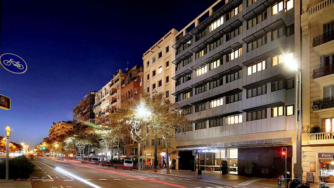 En gate i bymiljø om natten, med høye bygninger og biler langs veien. (AI-generert tekst)