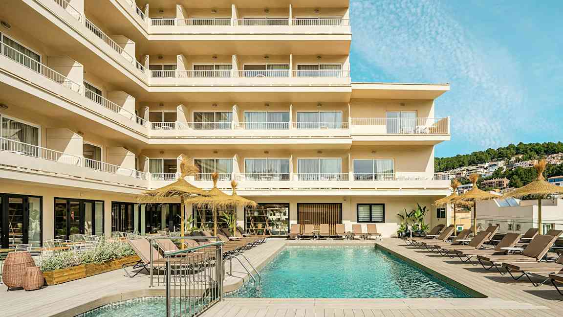 Bilde av et hotell med balkonger og et utendørsbasseng omgitt av solsenger. (AI-generert tekst)