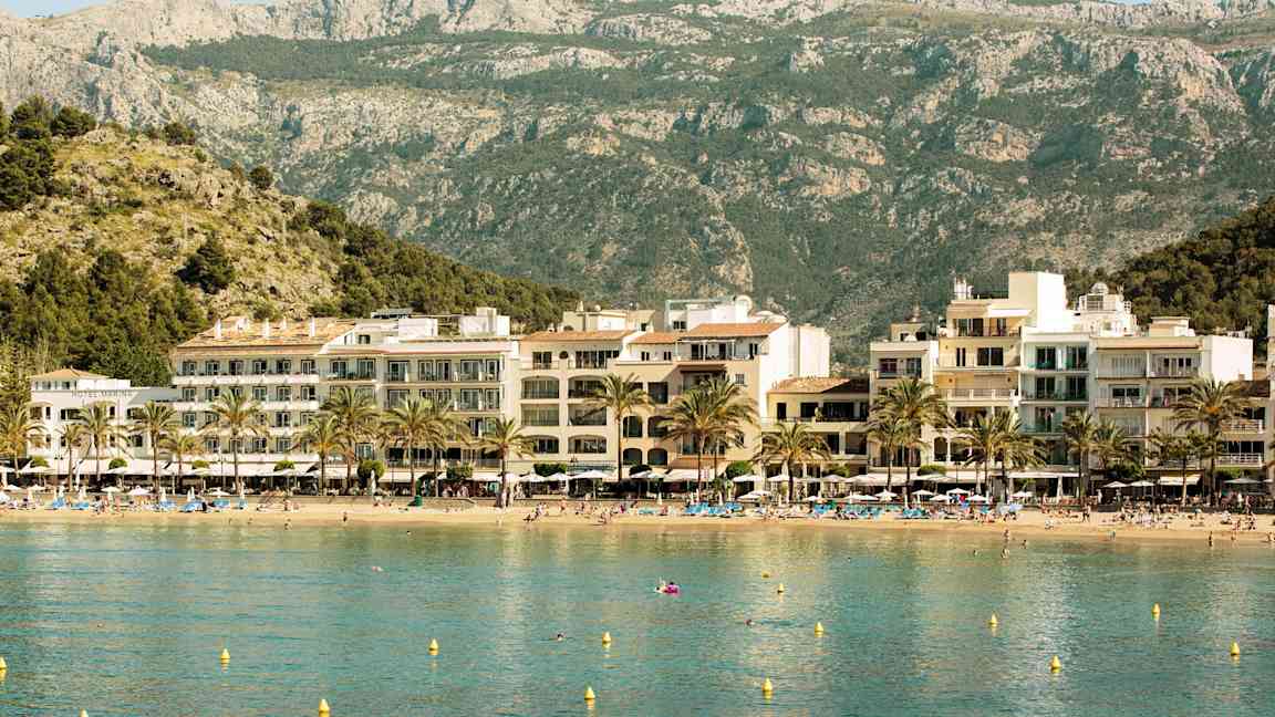 Strand med hotell og fjell i bakgrunnen. (AI-generert tekst)