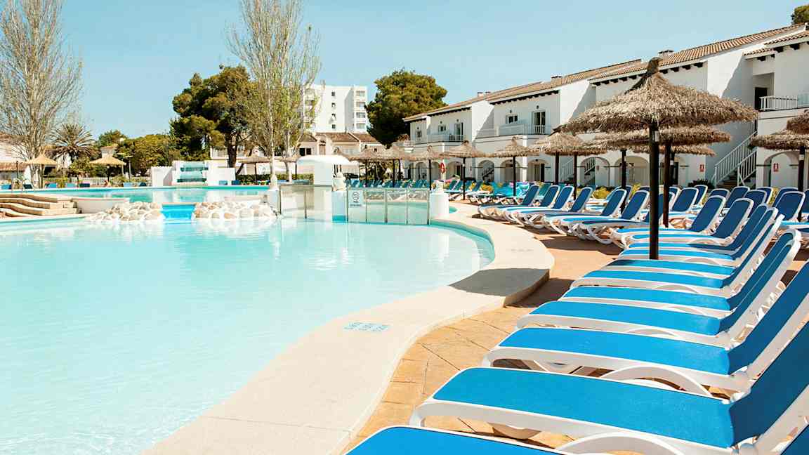 Et utendørs basseng med solsenger langs kanten under solfylte forhold. (AI-generert tekst)