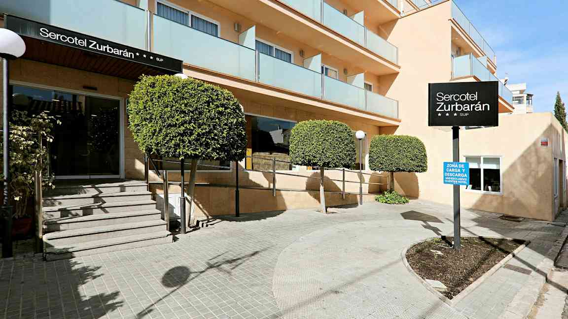 Bilde av inngangen til hotellet Sercotel Zurbarán med trær og balkonger. (AI-generert tekst)