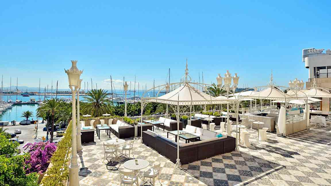 En romslig terrasse med sittegrupper, parasoller og havutsikt. (AI-generert tekst)