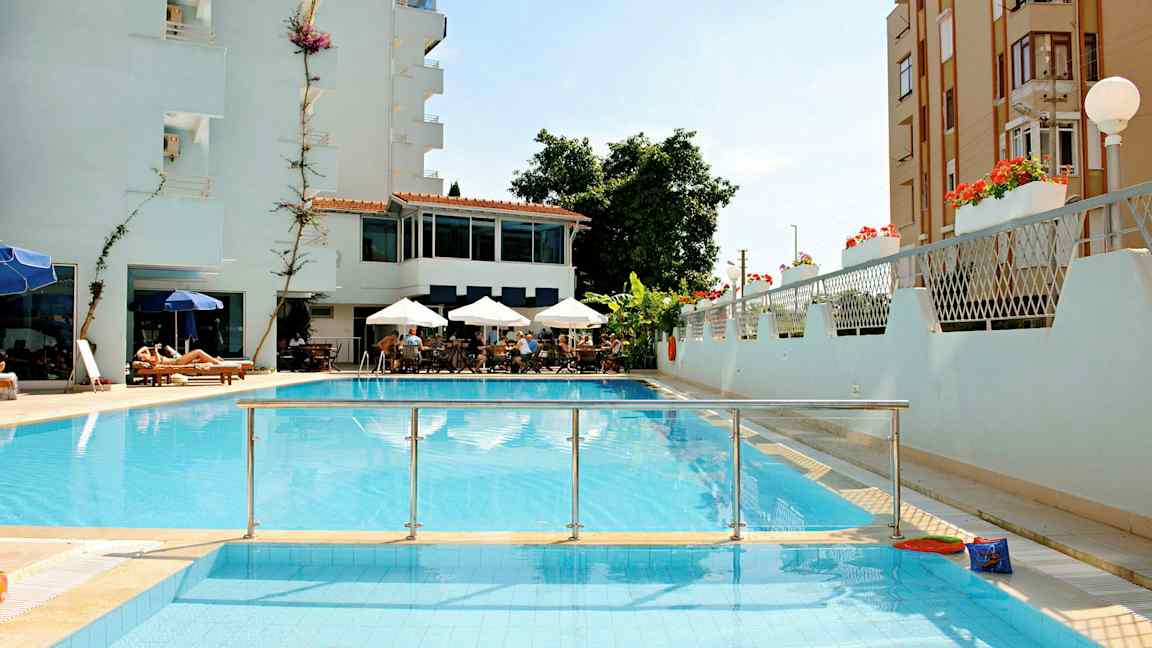 Et bilde av et hotell med basseng, sittegruppe med parasoller og solsenger. (AI-generert tekst)