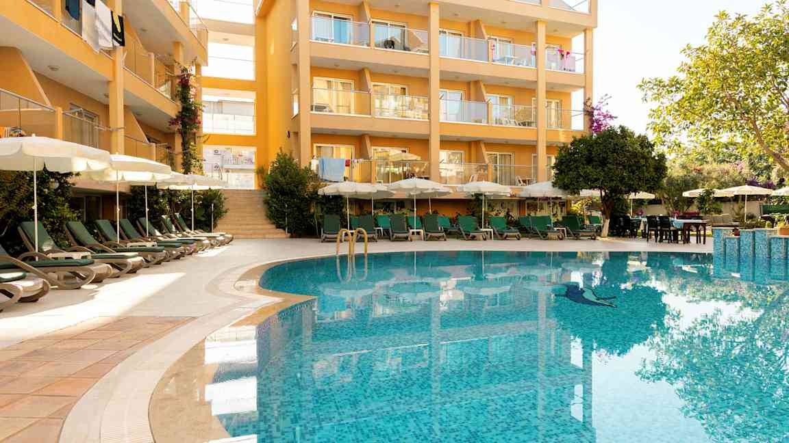 Bygning med balkonger og et basseng i forgrunnen. (AI-generert tekst)