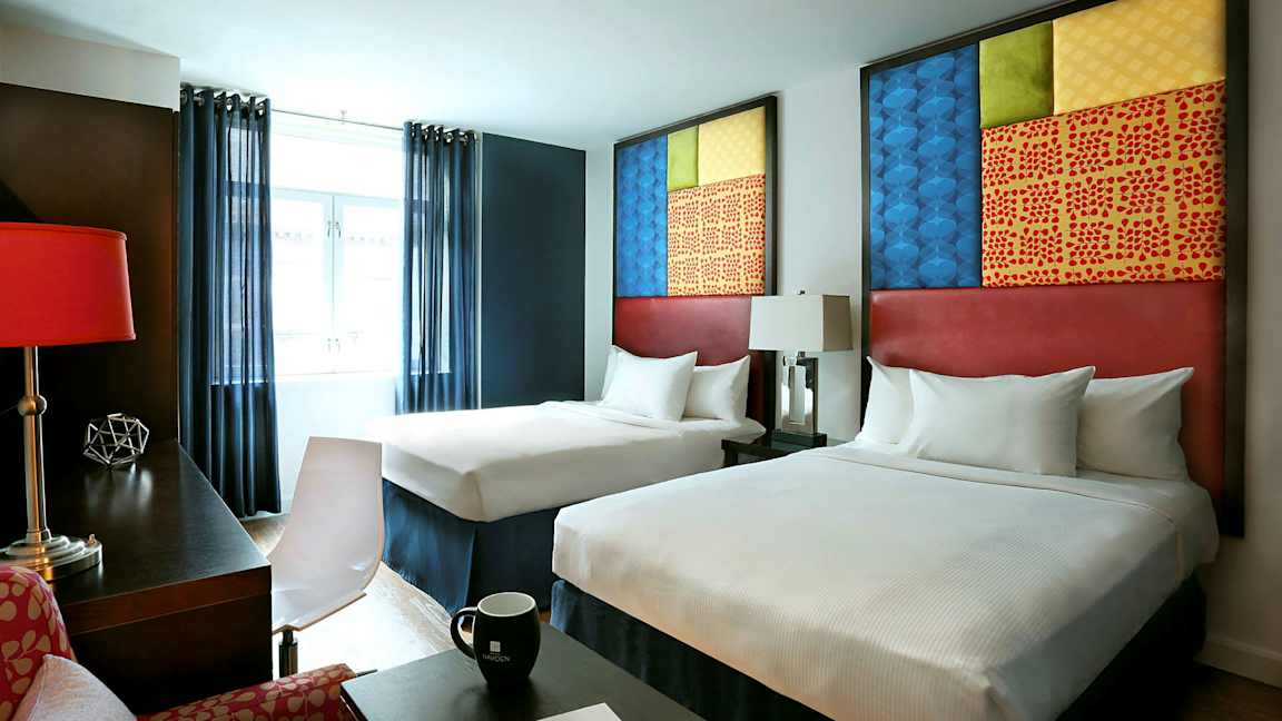 Hotellrom med to senger, moderne møbler og dekorative elementer. (AI-generert tekst)