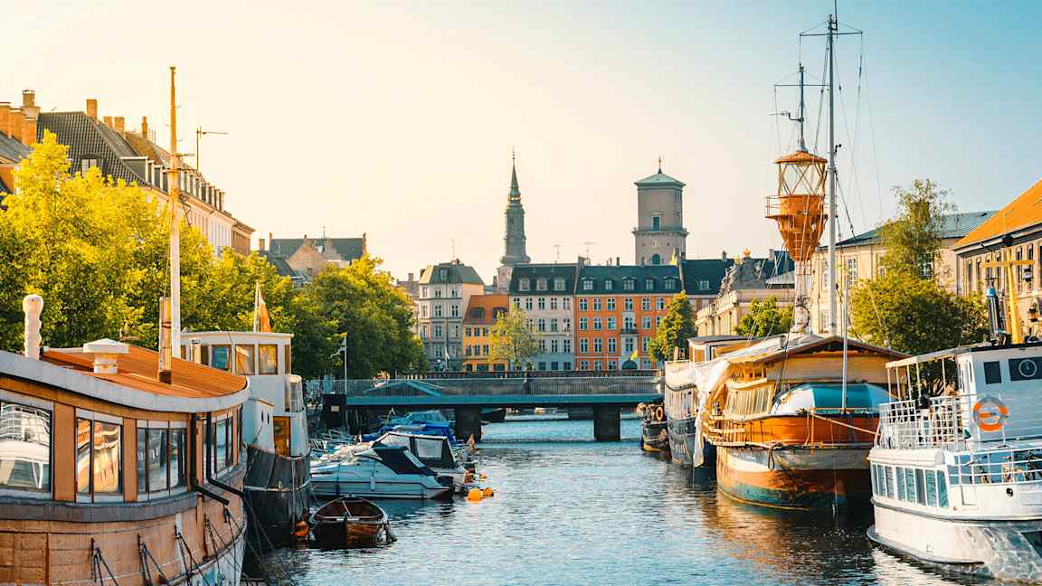 En bykanal med båter langs kantene og bygninger i bakgrunnen. (AI-generert tekst)