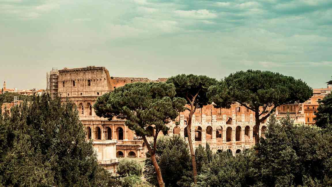 Utsikt over Colosseum i Roma, omgitt av trær. (AI-generert tekst)