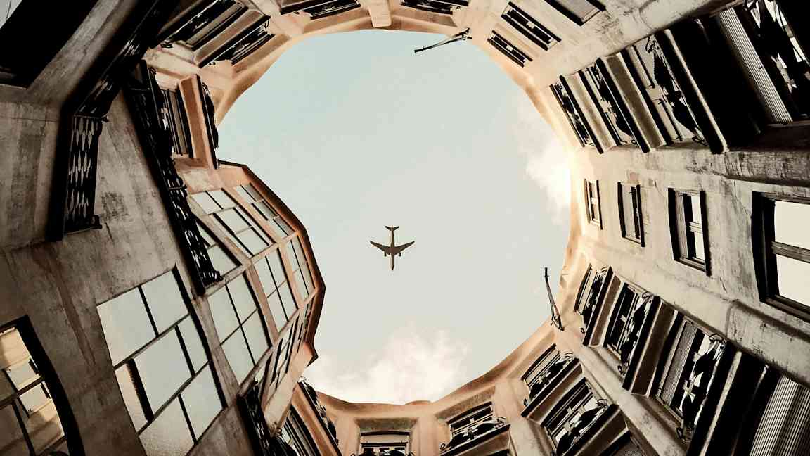 Et bilde av en flyselsilhuett mot himmelen sett fra bakgården til en bygning. (AI-generert tekst)