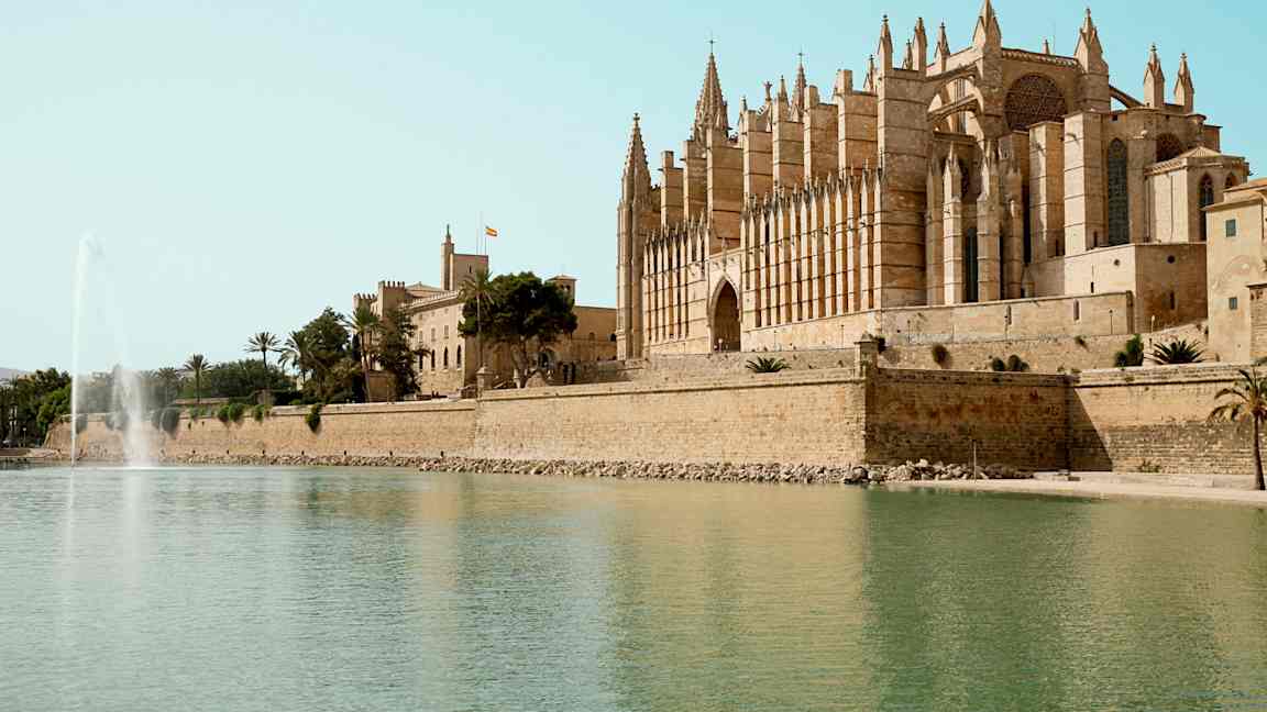 En katedral ved vannet med en fontene i forgrunnen. (AI-generert tekst)