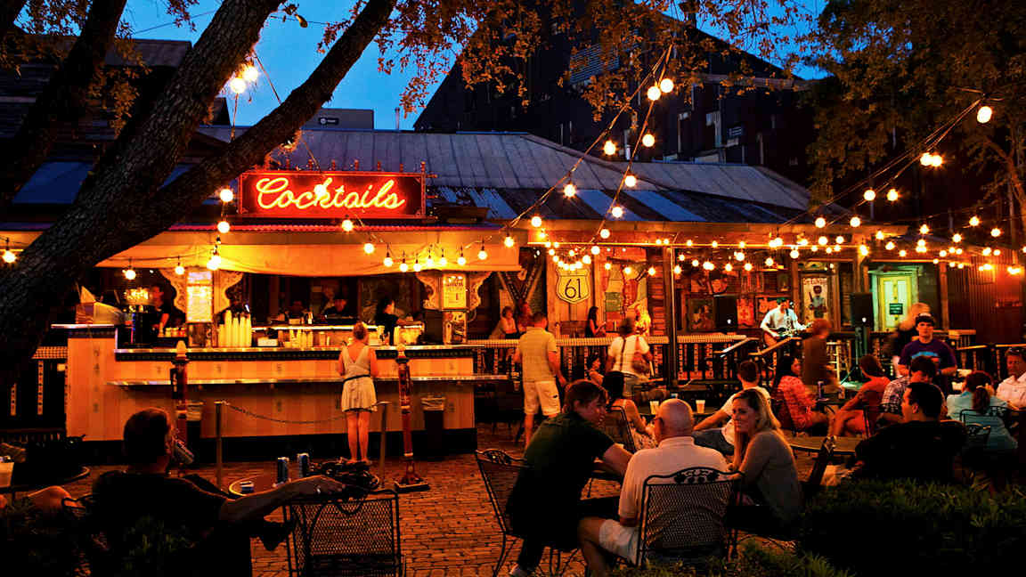 En utendørsbar med lys og gjester. (AI-generert tekst)