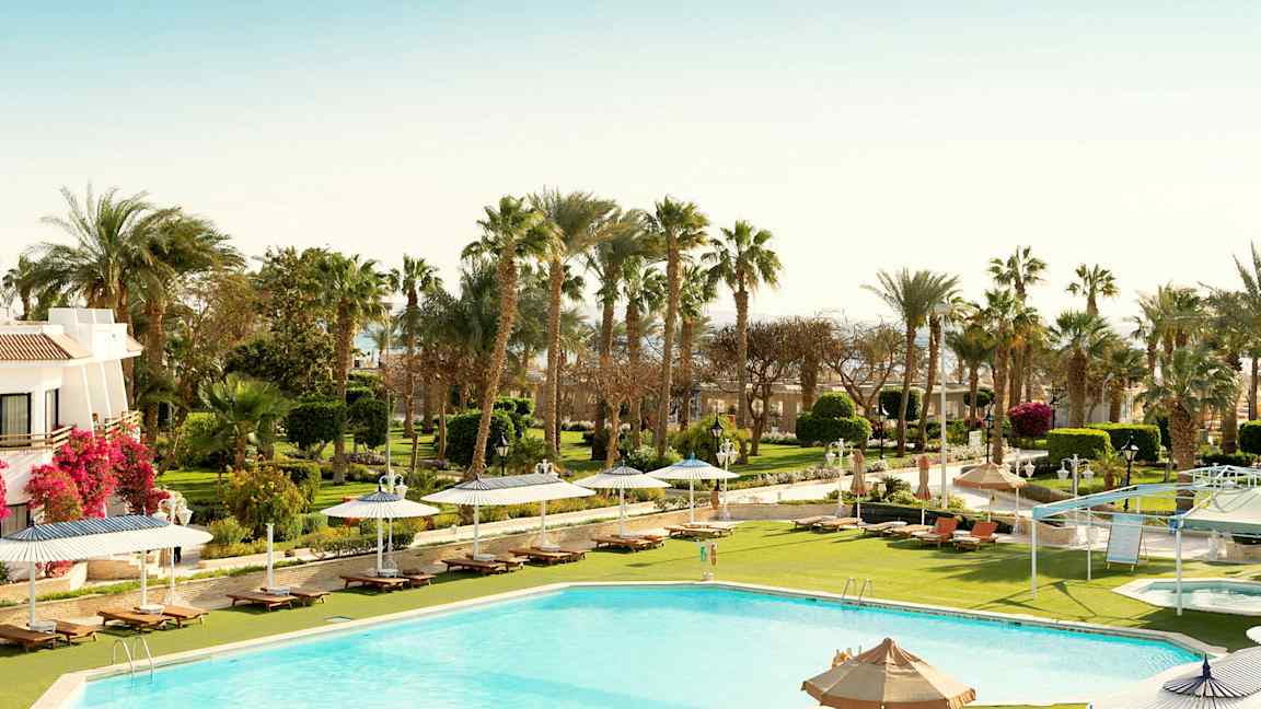 Basseng med solsenger, parasoller og grøntområder i bakgrunnen. (AI-generert tekst)