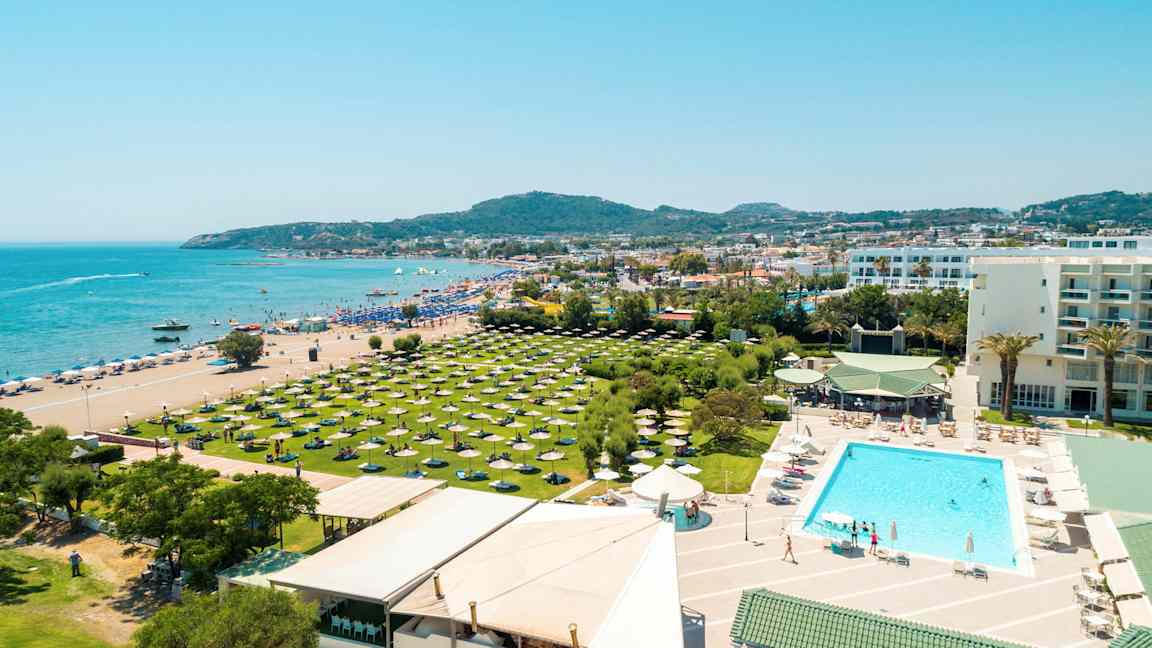 Postkort med utsikt over en strand, hotellets bassengområde og grøntområder med parasoller. (AI-generert tekst)