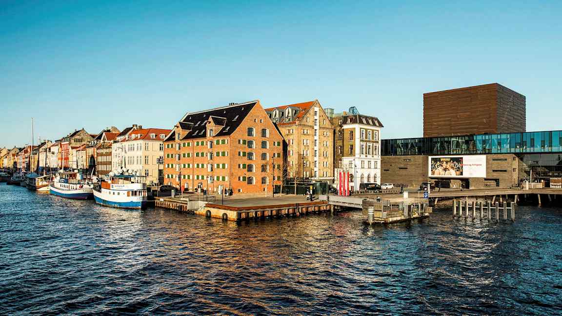 Bygninger ved en kanal med båter ved bryggen. (AI-generert tekst)