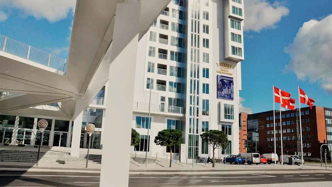 Moderne bygning med glassfasade ved siden av en gate. Danmarks flagg er synlige på flaggstenger. (AI-generert tekst)