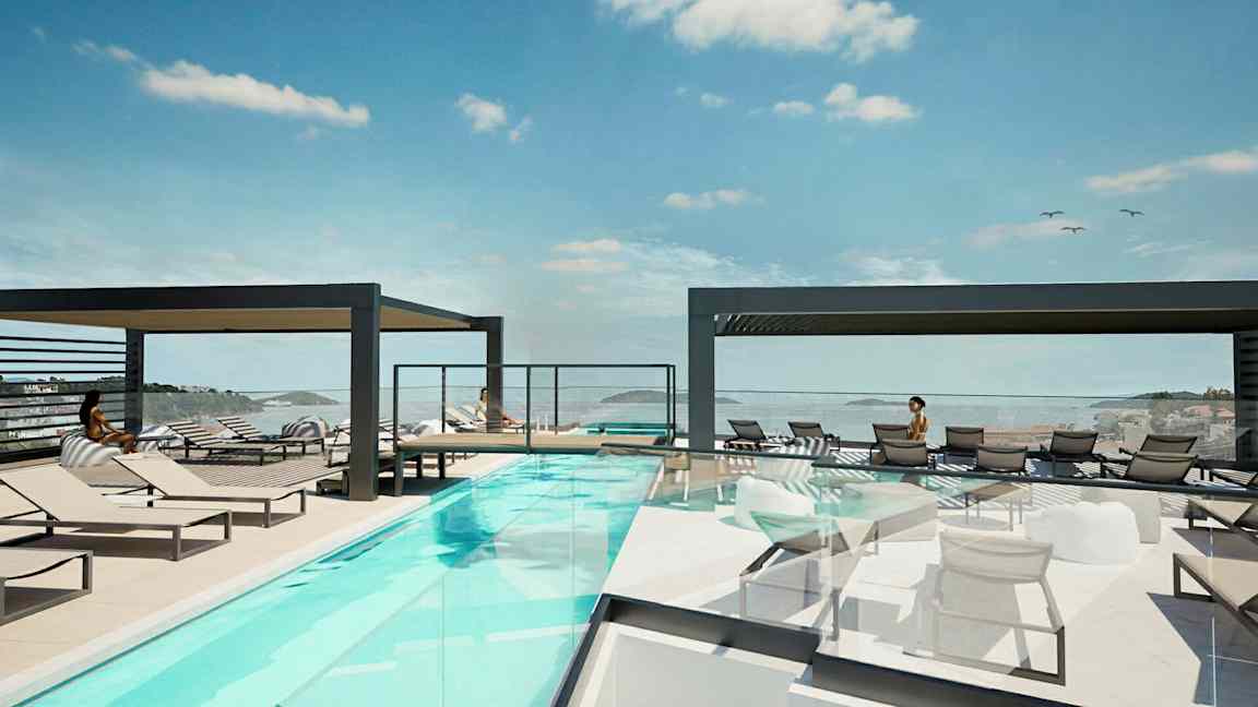 Et utendørsbasseng med solsenger og utsikt over havet. (AI-generert tekst)