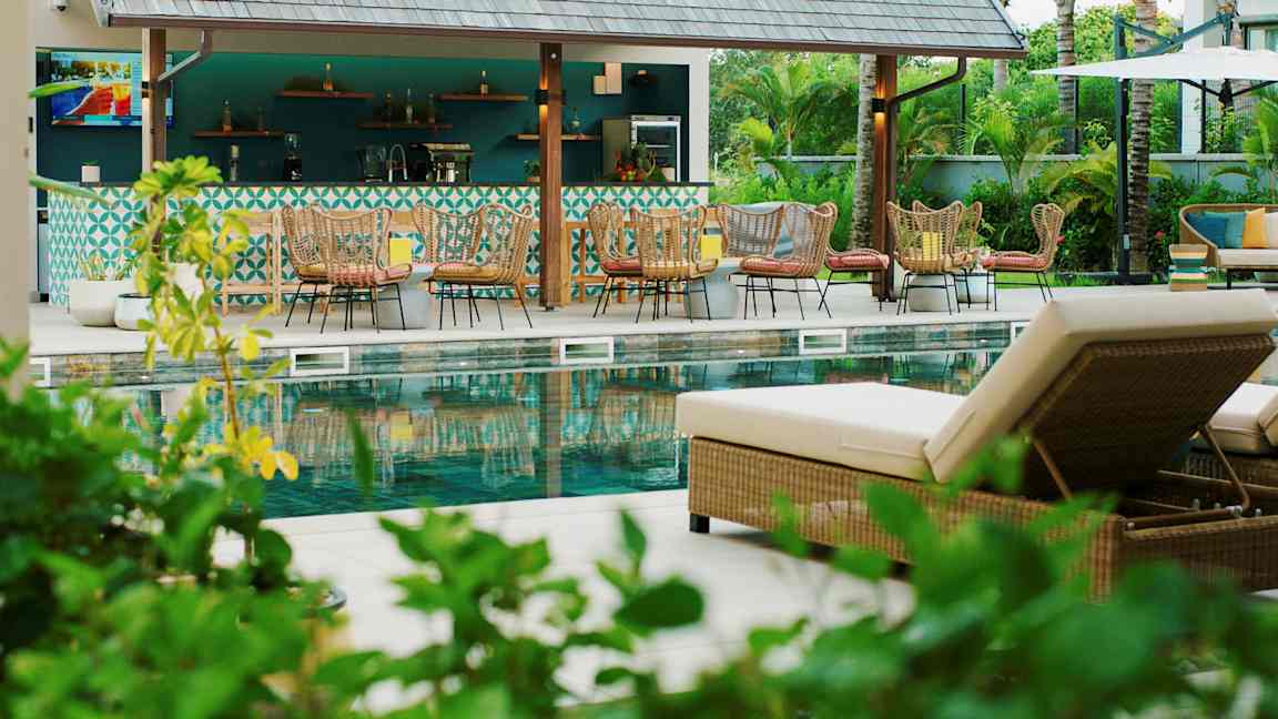 Bilde av et bassengområde med solsenger og en bar i bakgrunnen. (AI-generert tekst)