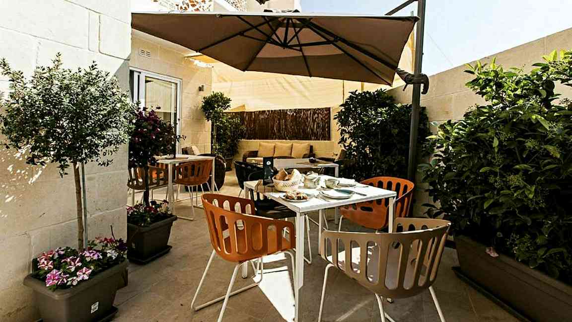 En terrasse med utemøbler, parasoll og planter. (AI-generert tekst)