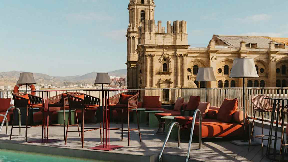 En takterrasse med basseng og loungemøbler, med en historisk bygning i bakgrunnen. (AI-generert tekst)