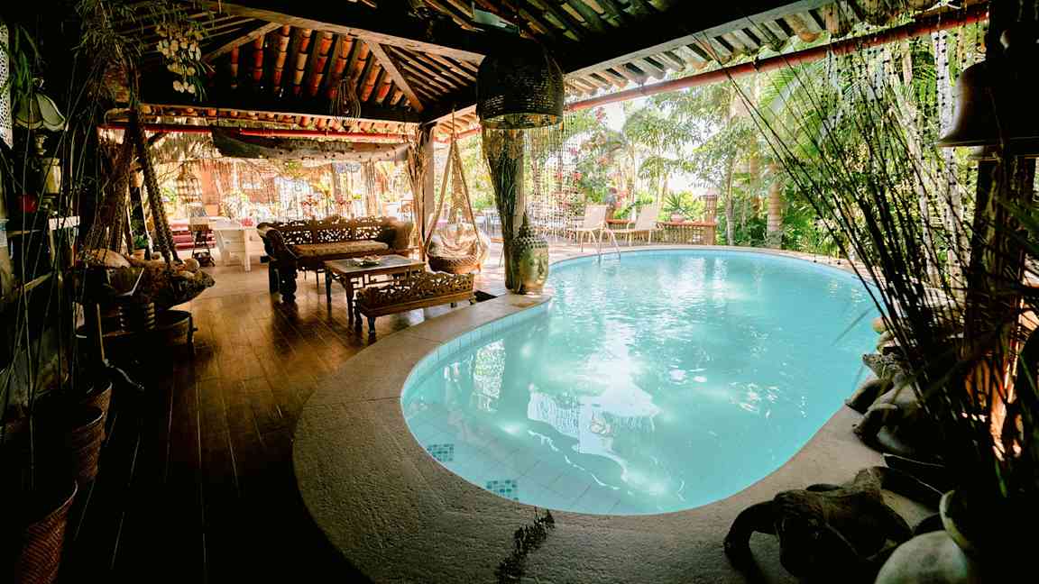Et koselig område med et innendørs basseng, tremøbler og planter rundt. (AI-generert tekst)