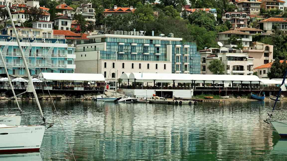 Bilde av en havn med båter og bygninger i bakgrunnen. (AI-generert tekst)