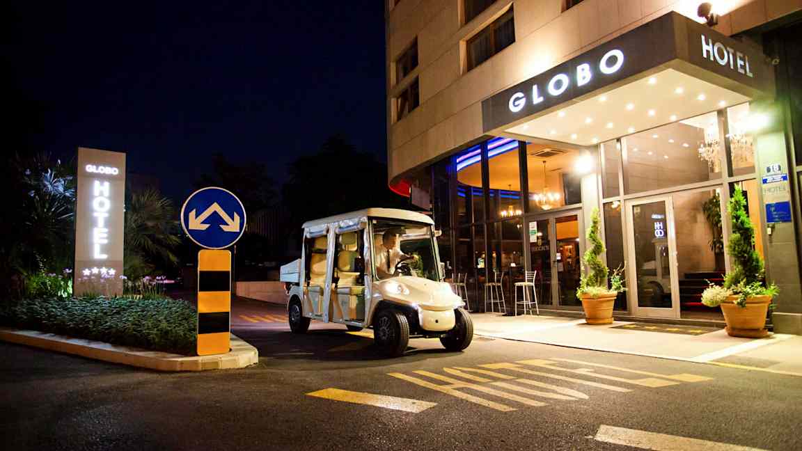 Et hotell sett om natten med navnet Globo, en elbil er parkert foran inngangen. (AI-generert tekst)