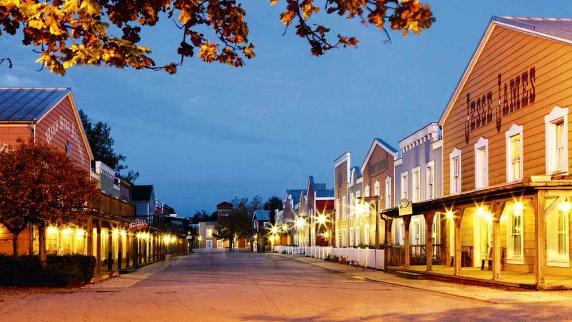 En opplyst gate med hus i westernstil og trær med høstløv. (AI-generert tekst)