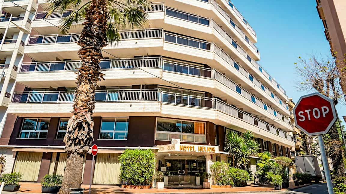 Et hotell med flere etasjer og et palmetre foran. Skiltet "STOP" er synlig til høyre. (AI-generert tekst)