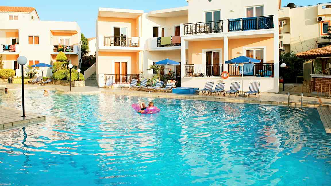 Leiligheter ved et utendørsbasseng med solsenger og parasoller. (AI-generert tekst)