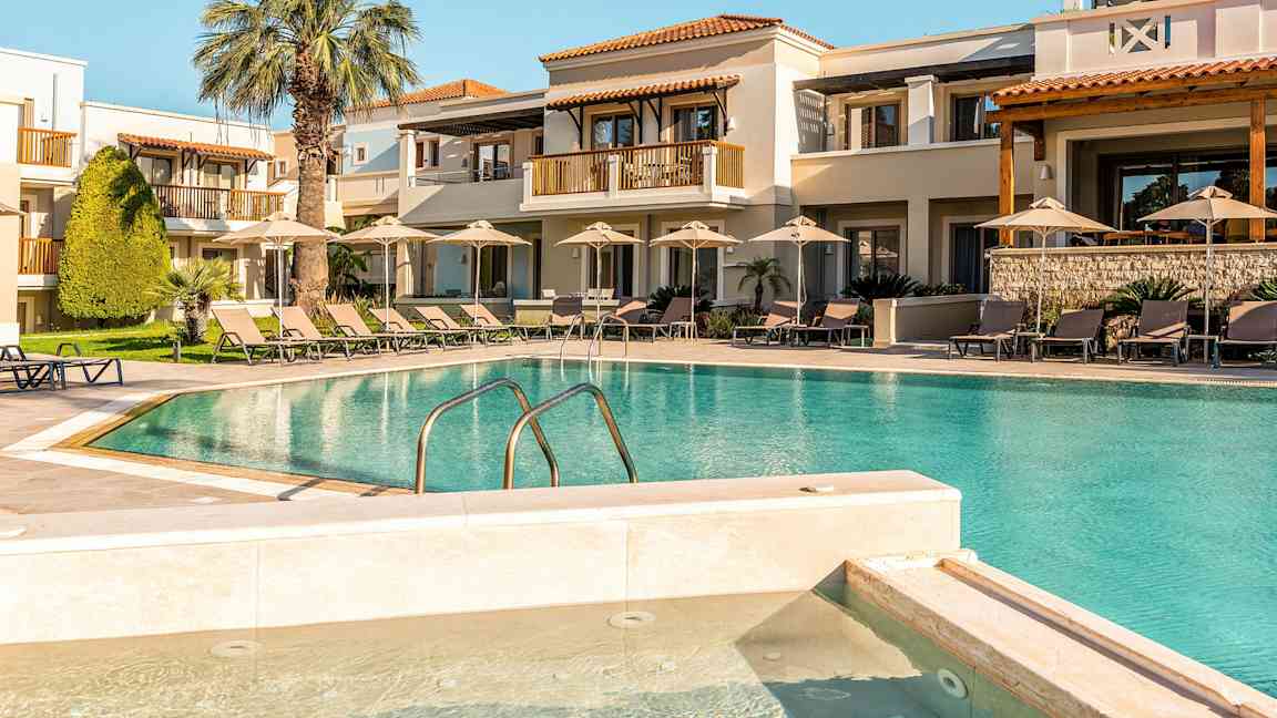 Hotellbygning med utendørsbasseng og solsenger. (AI-generert tekst)